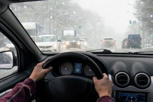 A woman driving in snowy conditions representing how you should call a Jamestown car accident lawyer.s