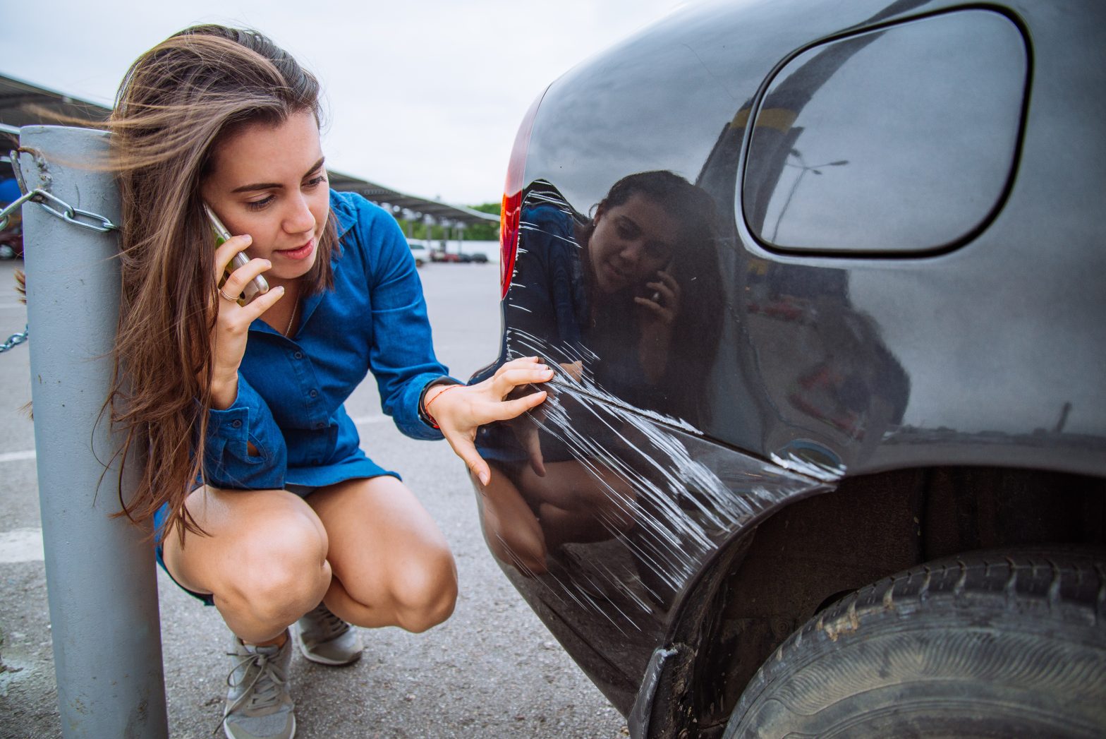 A woman is looking at damage to her car and calling Virginia car accident attorneys.